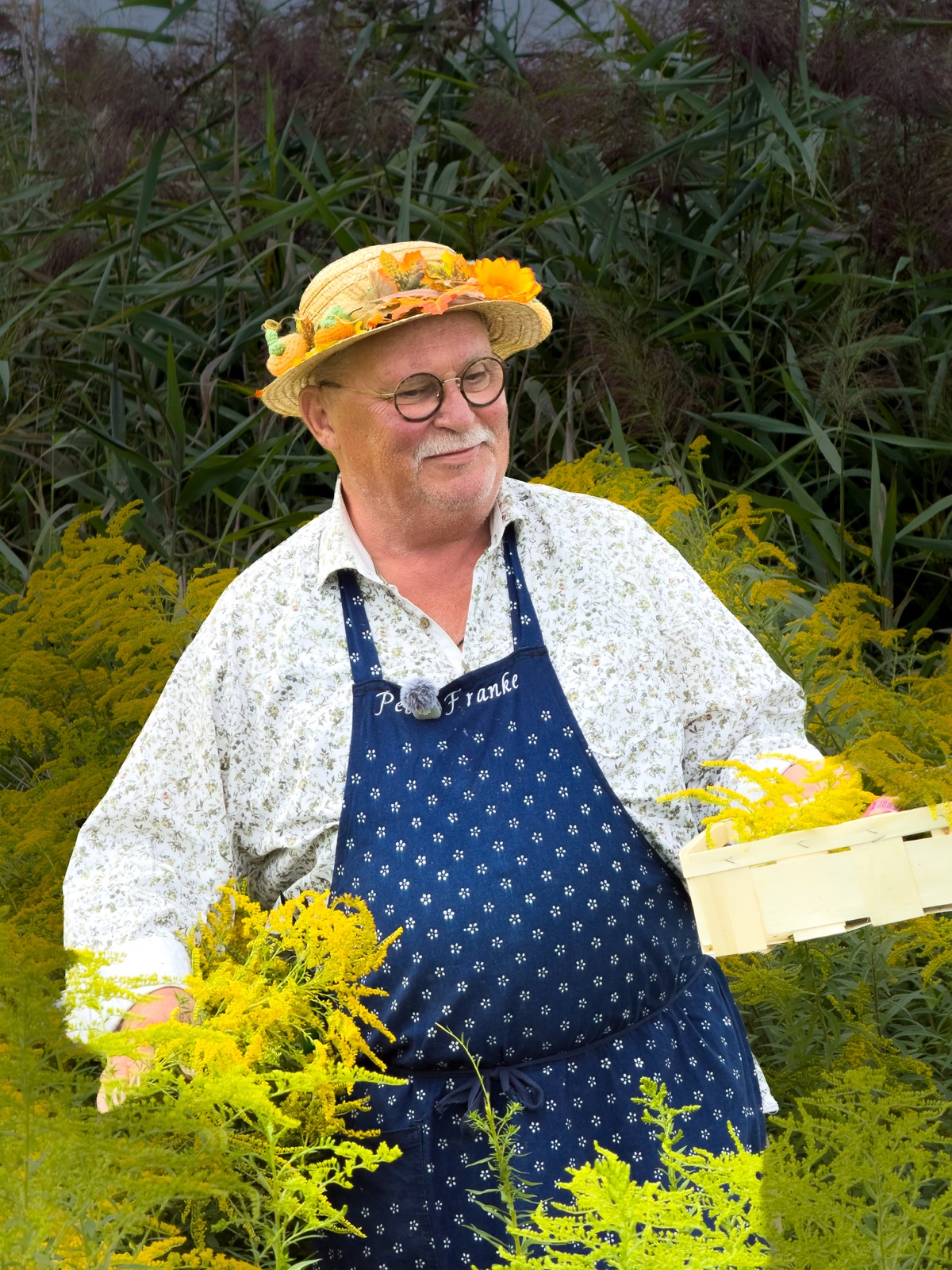 Peter Franke mit blumengeschmücktem Strohhut und Kräuterkorb